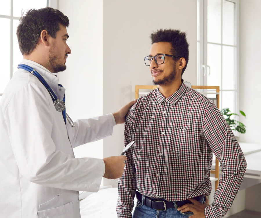 doctor talking to male patient, with his hand on patient's shoulder