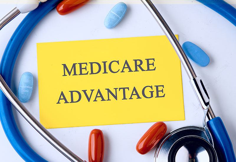 A sign that says "medicare advantage" with a stethoscope and pills around