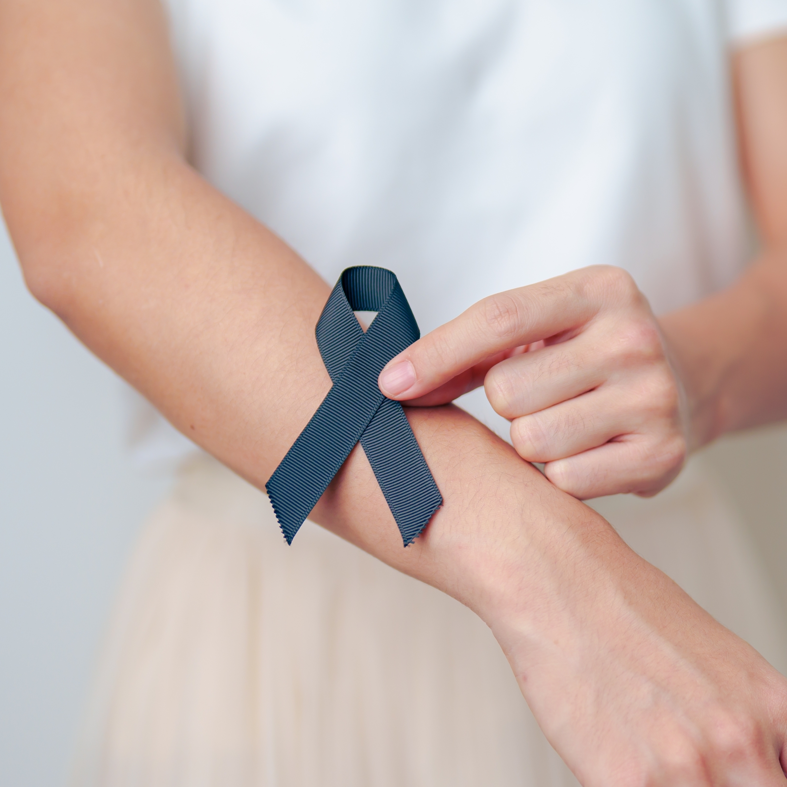 Woman holding a black ribbon signifying skin cancer awareness 