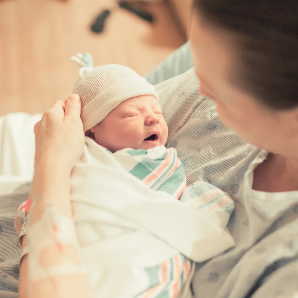 Mother holding newborn baby in hospital.