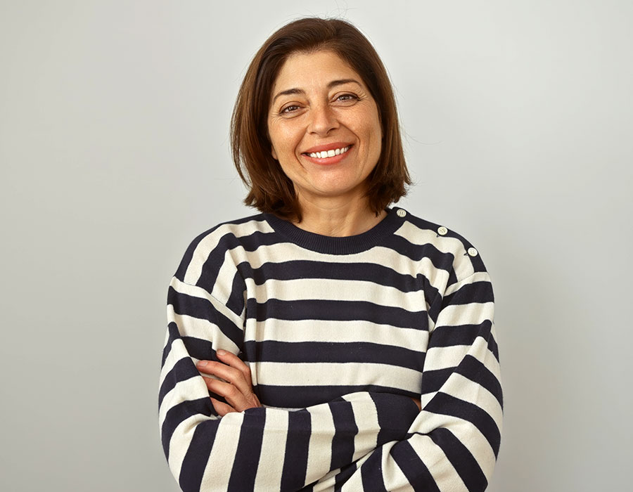 middle aged woman with arms crossed, smiling