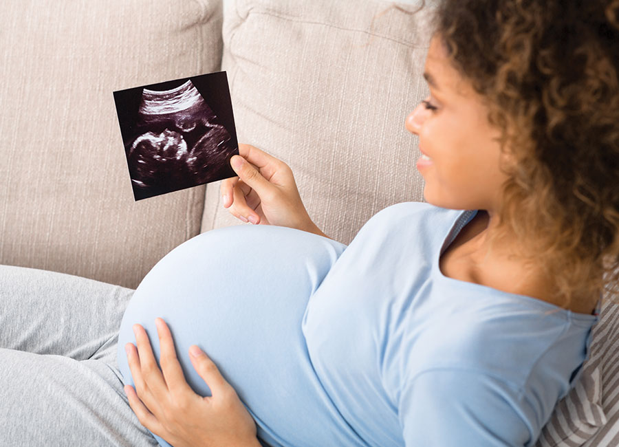 pregnant woman looking at sonogram photo