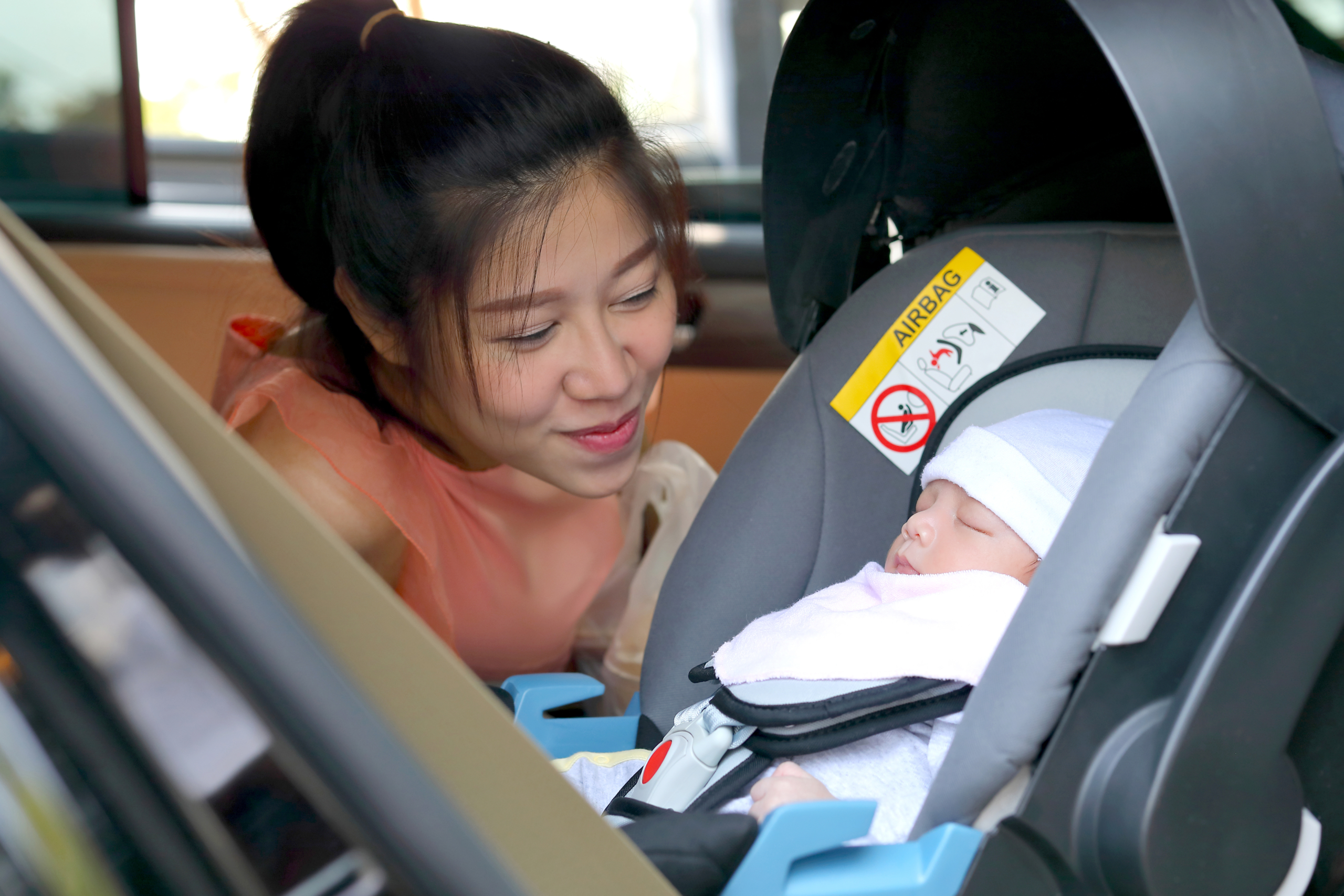 Mom looking lovingly at her newborn in a car seat